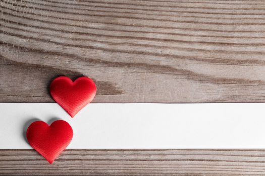 Valentine's day two red silk hearts and white paper on wooden background, love concept