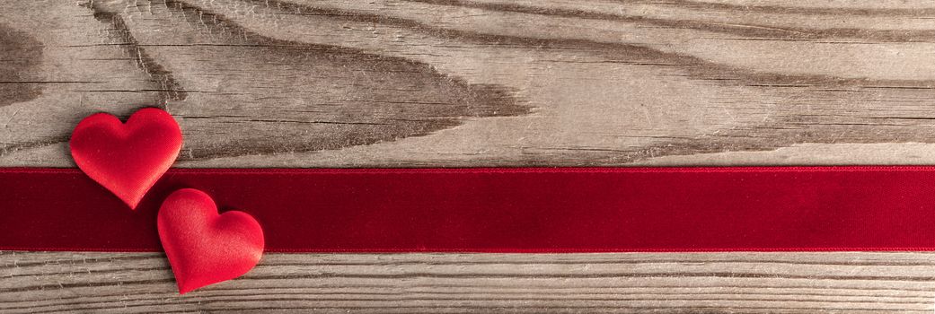 Valentine's day two red silk hearts and ribbon stripe on wooden background, love concept