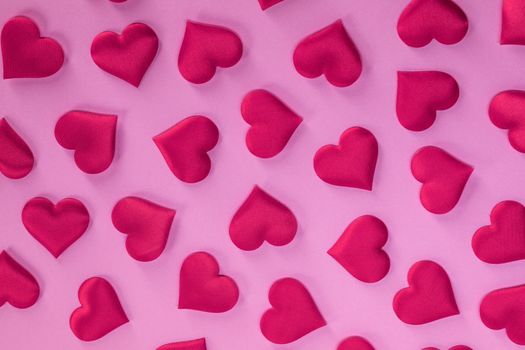 Valentine's day many red silk hearts on pink paper background, love concept
