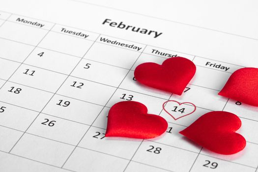 Valentine's day red silk hearts on calendar with 14 february date background, love, celebration concept