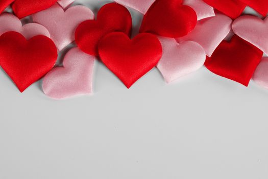 Valentine's day many red and pink silk hearts on white background , border frame with copy space, love concept