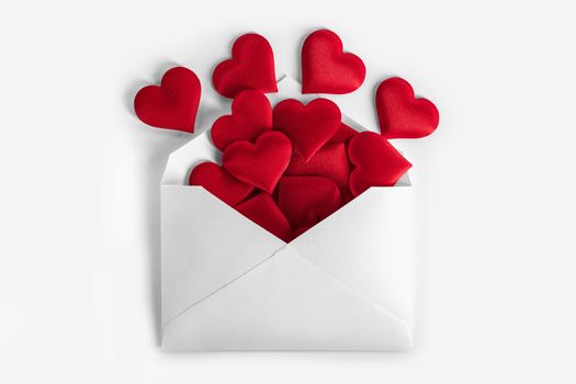 Valentine day love letter, envelope of craft paper with red hearts heap spread on white background.