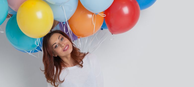 Young pretty woman in white with colored balloons on white background with copy space for text