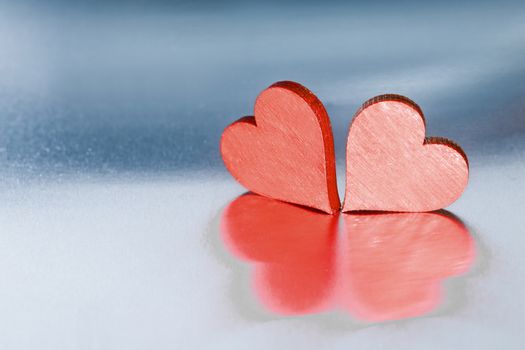 Two small handmade red wooden hearts on bright metal background Valentines day card