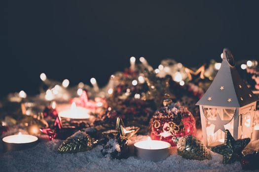 Lantern and christmas decoration on snow and garland lights background
