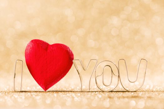 Red handmade wooden heart and words I love you on golden bright glitter lights bokeh background