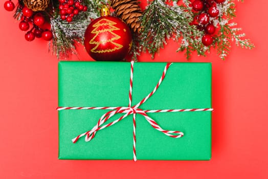 Christmas green gift box and decorations, fir tree branches on red background. Merry Christmas concept. With Copy space for text