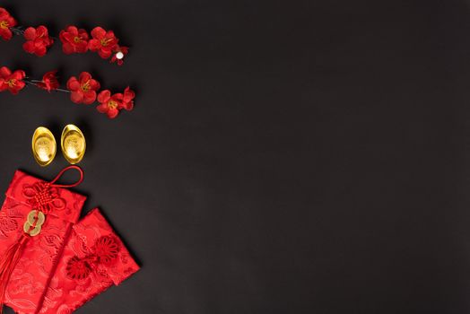 Chinese new year concept, flat lay top view, Happy Chinese new year with Red envelope and gold ingot (Character "FU" means fortune, blessing, wealth) on black background with copy space for your text