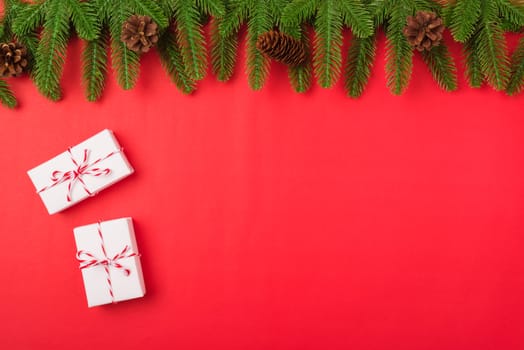 Happy new year or christmas day top view flat lay fir tree branches and gift box, decoration on red background with copy space for your text