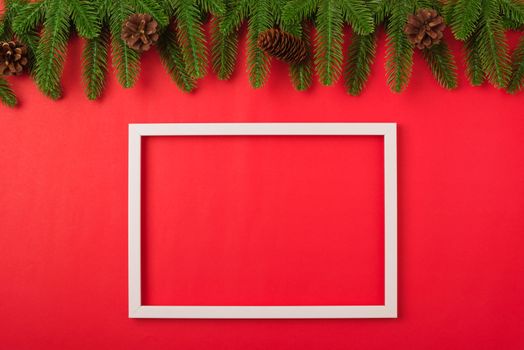Happy new year or christmas day top view flat lay fir tree branches and decoration photo fram on red background with copy space for your text