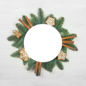 Christmas circle frame of natural fir tree branches and gingerbread cookies with copy space for text