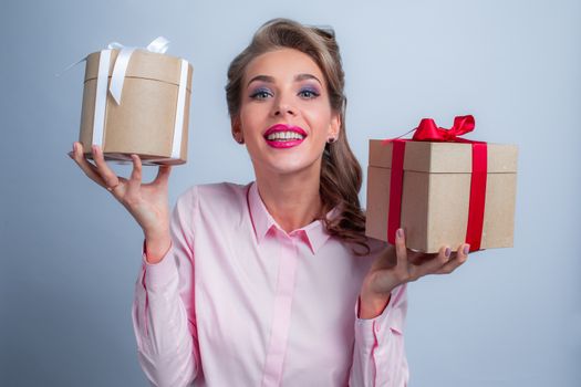 Young happy woman puts her ear to holiday presents with bows