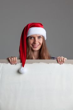 Santa girl holding blank vintage sign billboard. Christmas woman in Santa hat showing paper sign.