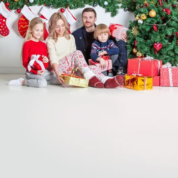 Cheerful family with Christmas gifts sitting near decorated Christmas tree