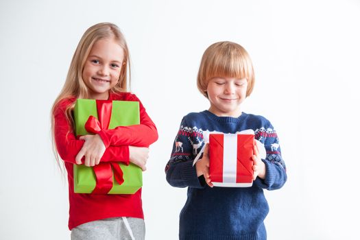 Portrait of two happy children with Christmas gift boxes on white background