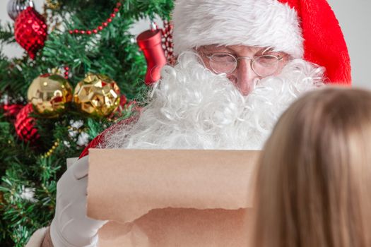 Santa Claus with with list or nice or naugthy list paper with small boy near christmas tree