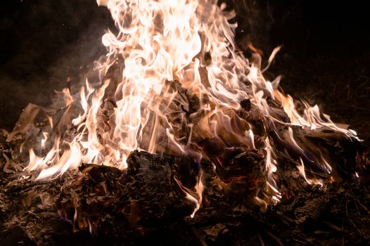 A low light underexposed photo of burning fire. Many sparks and flames. Burning books and wood. 