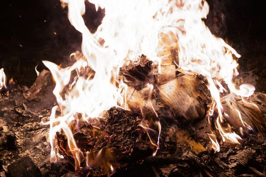 A low light underexposed photo of burning fire. Many sparks and flames. Burning books and wood. 