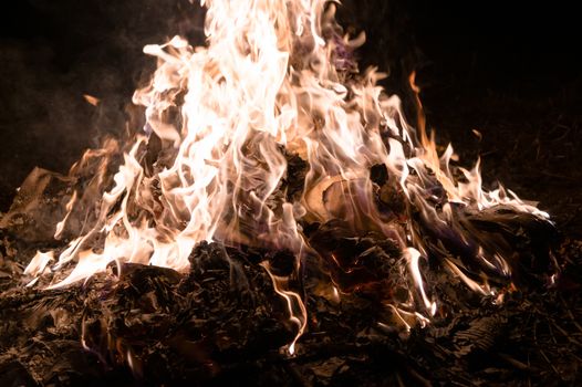 A low light underexposed photo of burning fire. Many sparks and flames. Burning books and wood. 