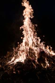 A low light underexposed photo of burning fire. Many sparks and flames. Burning books and wood. 