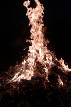 A low light underexposed photo of burning fire. Many sparks and flames. Burning books and wood. 