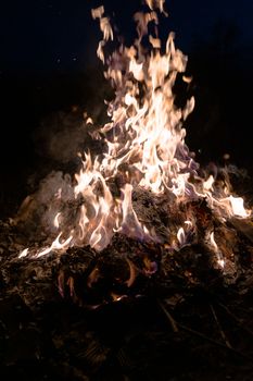 A low light underexposed photo of burning fire. Many sparks and flames. Burning books and wood. 