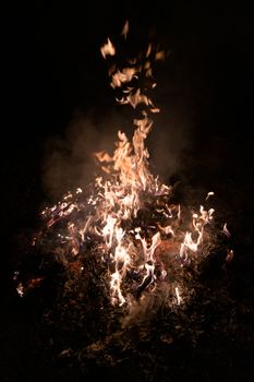 A low light underexposed photo of burning fire. Many sparks and flames. Burning books and wood. 