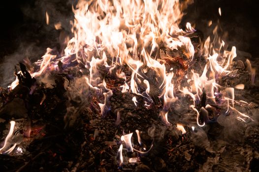 A low light underexposed photo of burning fire. Many sparks and flames. Burning books and wood. 