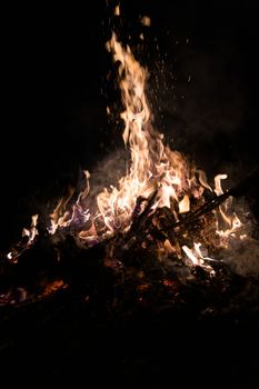 A low light underexposed photo of burning fire. Many sparks and flames. Burning books and wood. 