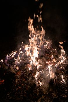 A low light underexposed photo of burning fire. Many sparks and flames. Burning books and wood. 