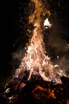 A low light underexposed photo of burning fire. Many sparks and flames. Burning books and wood. 