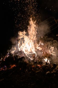 A low light underexposed photo of burning fire. Many sparks and flames. Burning books and wood. 