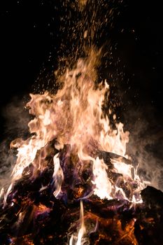 A low light underexposed photo of burning fire. Many sparks and flames. Burning books and wood. 