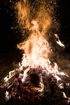 A low light underexposed photo of burning fire. Many sparks and flames. Burning books and wood. 