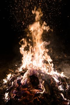 A low light underexposed photo of burning fire. Many sparks and flames. Burning books and wood. 