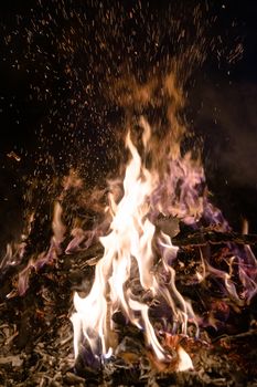 A low light underexposed photo of burning fire. Many sparks and flames. Burning books and wood. 