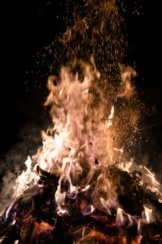 A low light underexposed photo of burning fire. Many sparks and flames. Burning books and wood. 