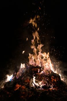 A low light underexposed photo of burning fire. Many sparks and flames. Burning books and wood. 