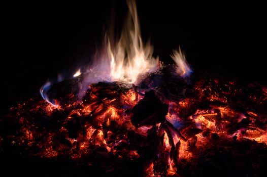 A low light long exposure photo of smouldering coals. Many coals and flames. Burning books and wood. 