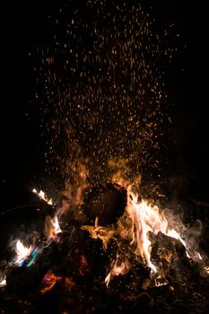 A low light underexposed photo of burning fire. Many sparks and flames. Burning books and wood. 