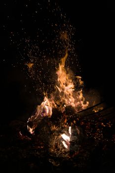 A low light underexposed photo of burning fire. Many sparks and flames. Burning books and wood. 