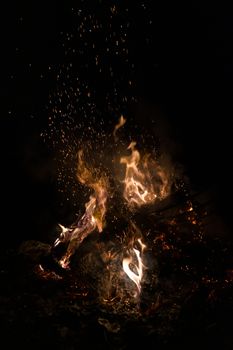 A low light underexposed photo of burning fire. Many sparks and flames. Burning books and wood. 