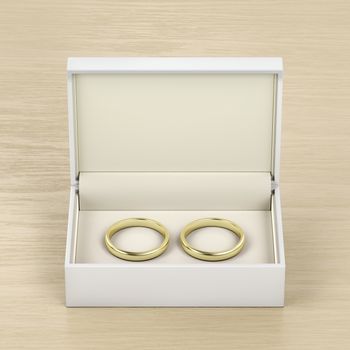 White box with gold wedding rings on wood table