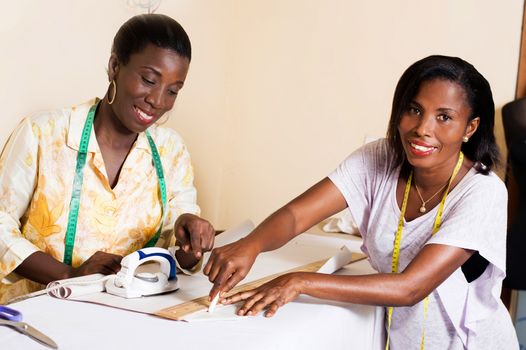 Happy student draws a line on paper in the presence of her sewing teacher.