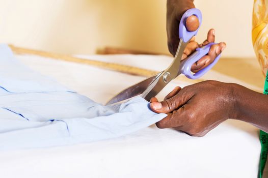 A seam cutting a piece of cloth on his table.
