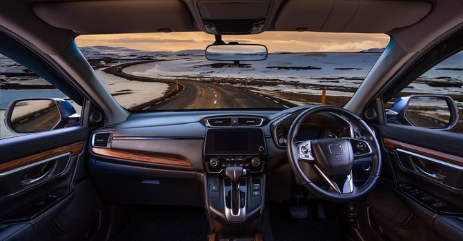 Looking through a car windshield with sunset and road in winter. Travel in car.