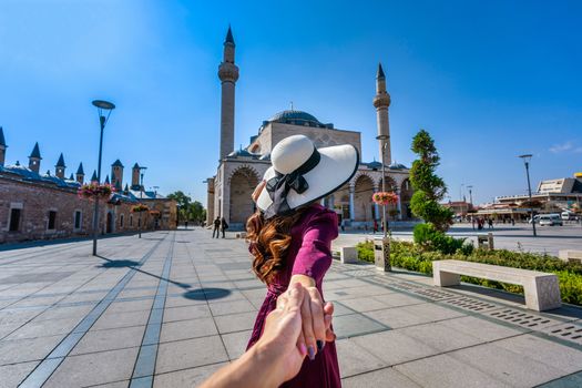 Women tourists holding man's hand and leading him to mosque in Konya, Turkey.