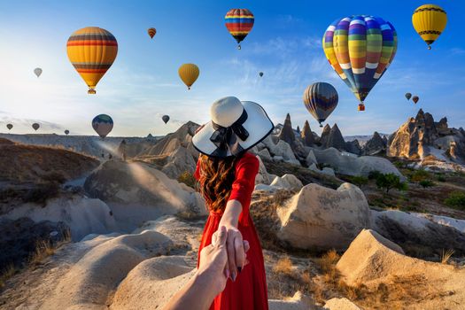 Women tourists holding man's hand and leading him to hot air balloons in Cappadocia, Turkey.