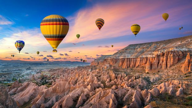 Hot air balloons and Red valley  at sunset in Goreme, Cappadocia in Turkey.