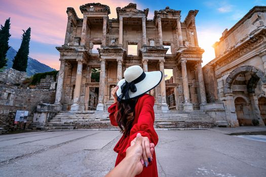 Women tourists holding man's hand and leading him to Celsus Library at Ephesus ancient city in Izmir, Turkey.